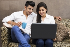 man with coffee looking at woman browsing in laptop