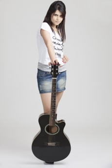 girl wearing short denims posing with a guitar