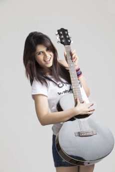 girl wearing short denims posing with a guitar