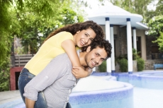 man carrying woman on back outside villa 