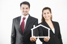 couple dressed as real estate agents holding home frame 