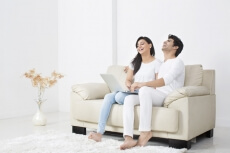 couple on couch having leisure time while browsing in laptop