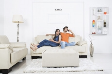 man on couch talking on phone with girl sitting beside