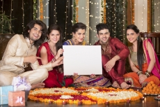 couples in traditional wear sitting with a message board 