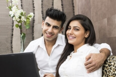 couple with laptop looking at the camera and posing