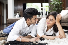 couple lying on rugs and looking at each other