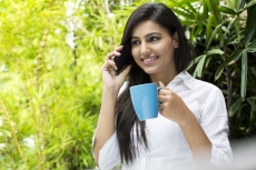 attractive female talking on the phone while having coffee