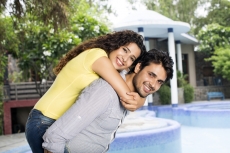 man carrying woman on back outside villa