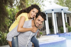 man carrying woman on back outside villa