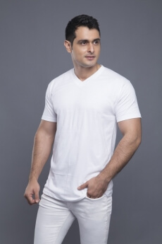man in white standing with hands in pockets 