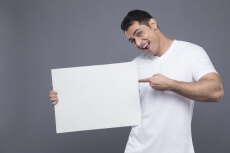 man in white posing with a message board 