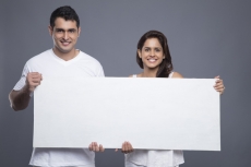 young couple holding a blank poster