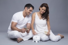happy couple depositing money in the piggy bank