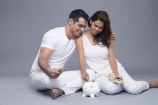 happy couple depositing money in the piggy bank