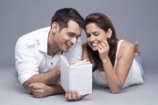 couple reading a book while lying in front view