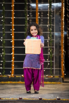 cheerful small girl offering a present on diwali