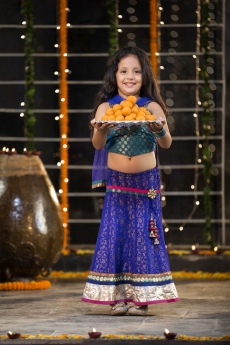 sweet girl holding a thali of laddu on diwali