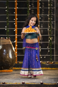 sweet girl holding a thali of laddu on diwali