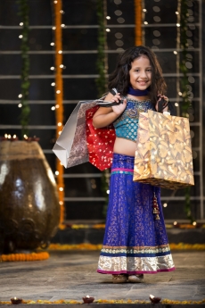 cheerful little girl carrying shopping bags on diwali