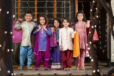 five small kids dressed in traditional outfit holding shopping bags