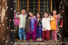 five small kids dressed in traditional outfit holding shopping bags
