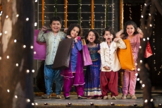 five small kids dressed in traditional outfit holding shopping bags