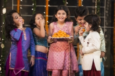 group of kids eating laddu on diwali