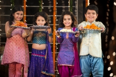 group of kids standing and offering sweets on diwali