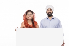 sikh couple standing with a message board 