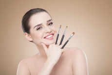girl posing with make up brush and smiling
