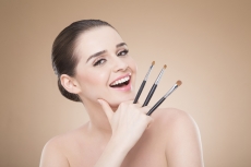 girl posing with make up brush and smiling