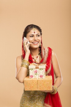 woman talking on phone while holding gifts