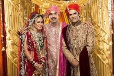 bride and groom posing with father 