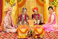 indian bride and groom sitting with parents at mandap