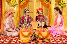 indian bride and groom sitting with parents at mandap