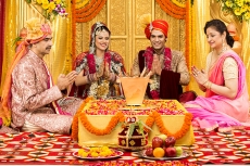 indian bride and groom sitting with parents at mandap