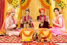 indian bride and groom sitting with parents at mandap