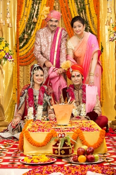 indian bride and groom sitting with parents at mandap