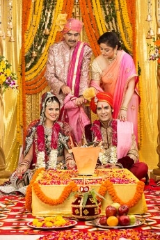indian bride and groom sitting with parents at mandap