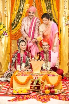 indian bride and groom sitting with parents at mandap