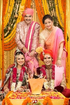 indian bride and groom sitting with parents at mandap