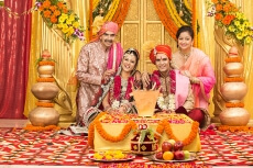indian bride and groom sitting with parents at mandap
