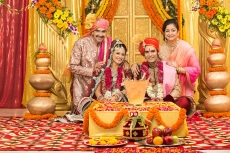 indian bride and groom sitting with parents at mandap