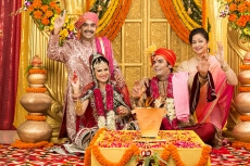indian bride and groom sitting with parents at mandap