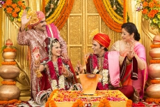 indian bride and groom sitting with parents at mandap