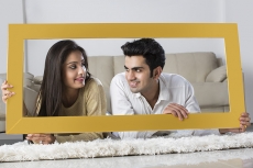 young couple posing with wooden frame at home