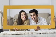 young couple posing with wooden frame at home
