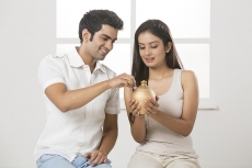 newly wed couple at new home with piggy bank