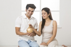 newly wed couple at new home with piggy bank
