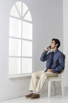 man sitting on chair talking on mobile phone